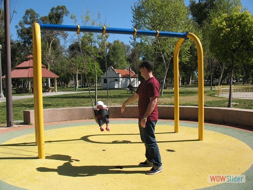 a father and his baby play on the swingset